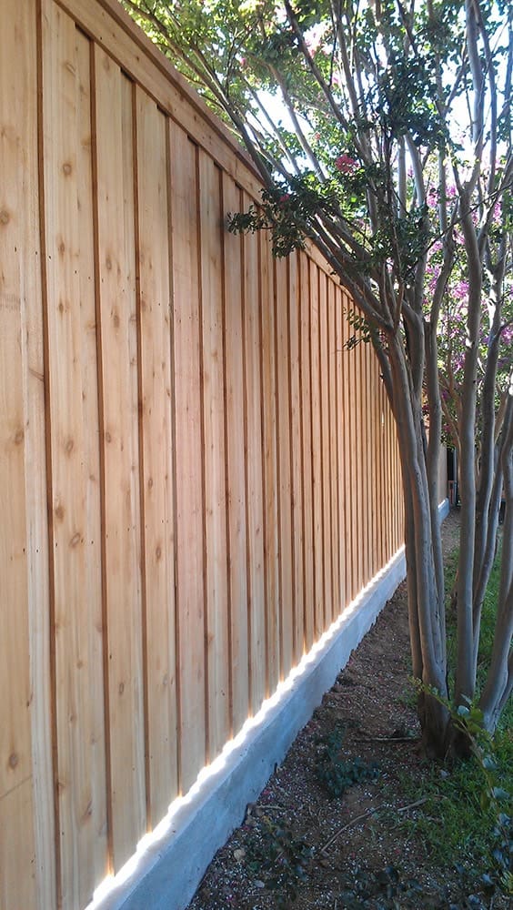 Natural cedar stained board on board with cap and trim wood fence
