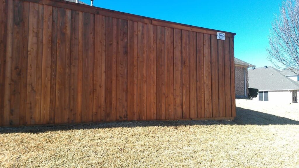 Stained board on board fence with kickboard, cap, and trim