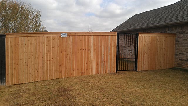 Side by side cedar fence with cap, trim, and iron gate