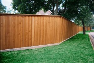 Board on Board Style Residential Wood Fence surrounded by a lawn and trees