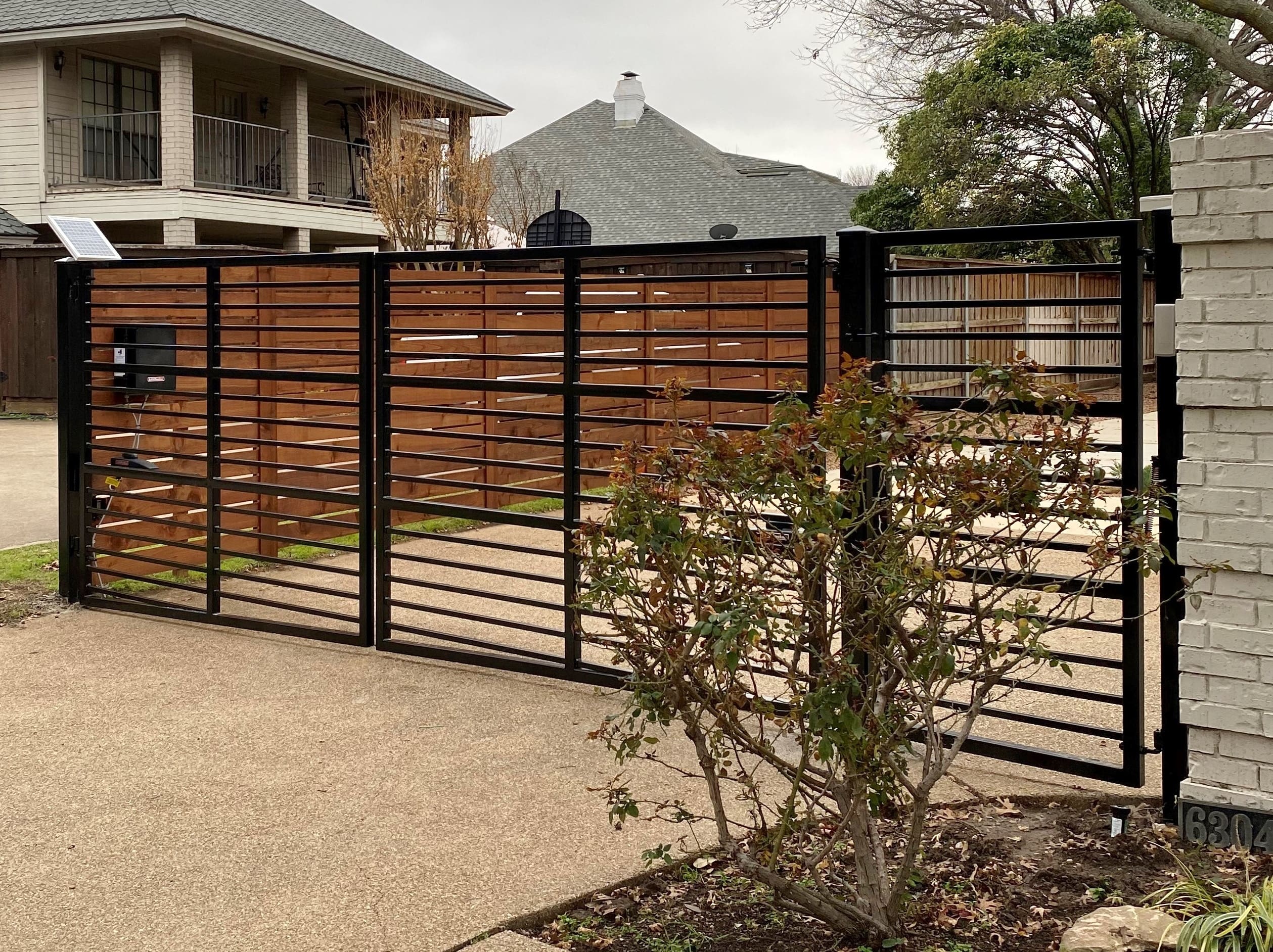 Black Iron gate with horizontal bars on paved driveway