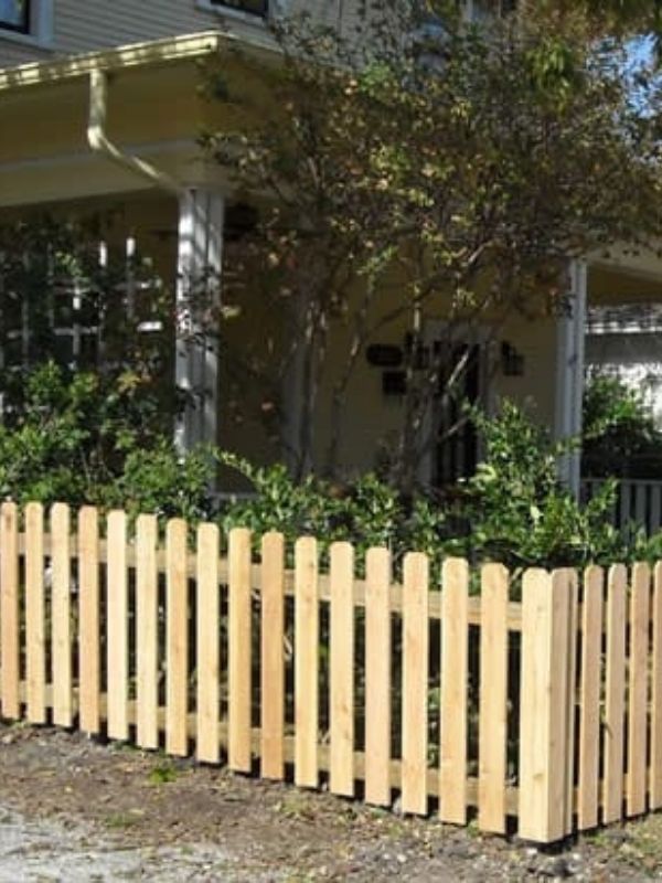 A short cedar picket fence in front of a home.