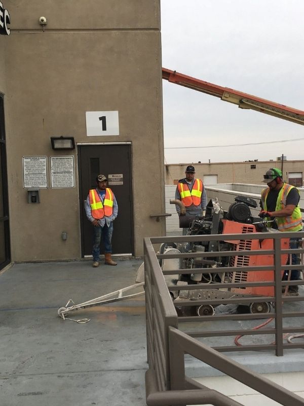 Crew operating machinery and prepping concrete outside of a commercial building