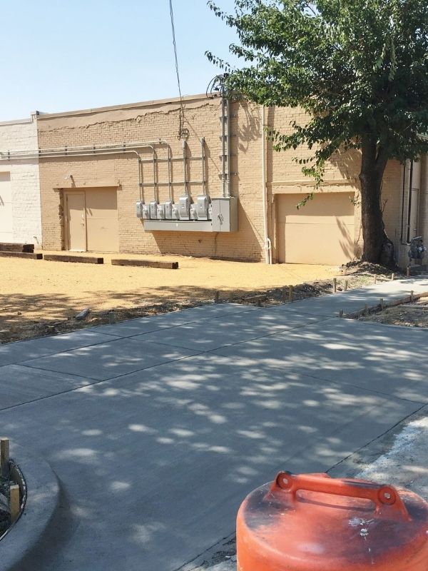 Concrete sidewalk and driveway poured near brick building.