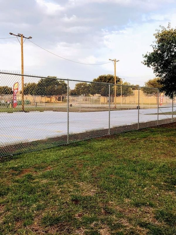 A chain-link fence next to a parking lot.