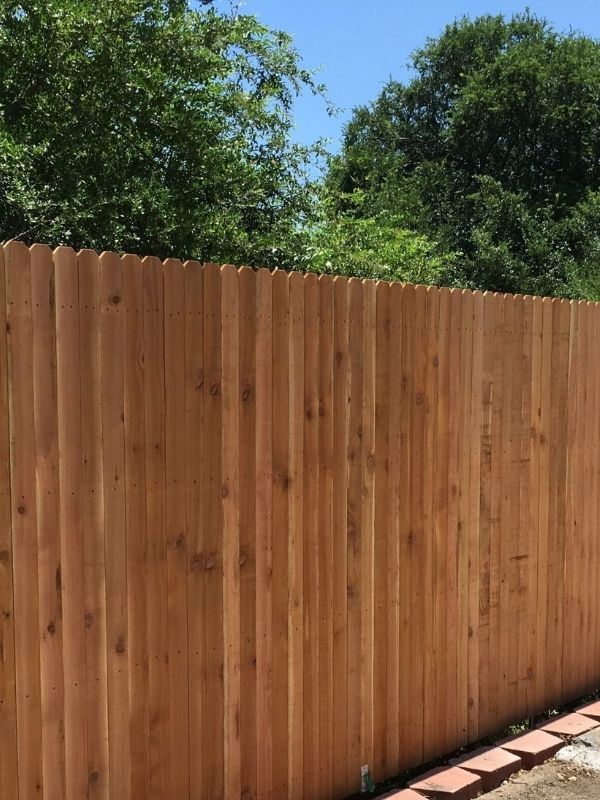 A residential wood fence in front of trees.